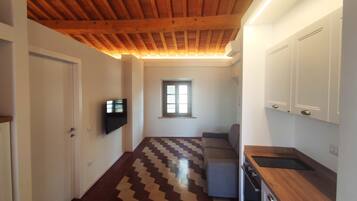 A modern kitchen with a wooden ceiling, a built-in oven, and a window with blinds.