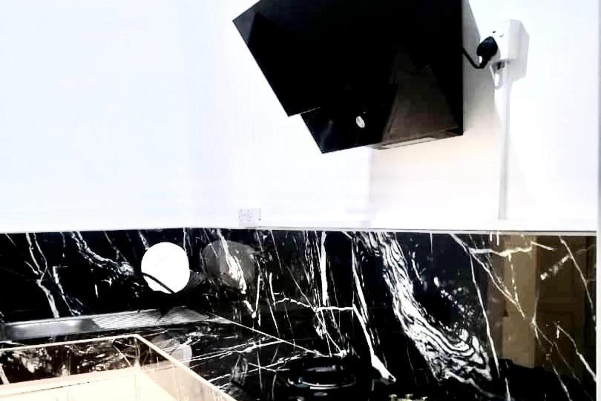 Un baño con pared blanca y encimera negra.