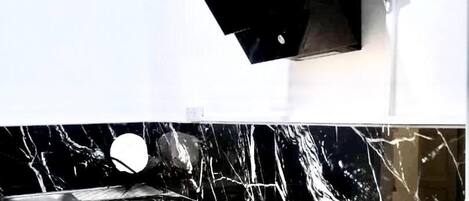 A bathroom with a white wall and a black countertop.