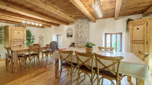 Un coin repas en bois avec une longue table et des chaises, un mur en pierre et des armoires en bois.