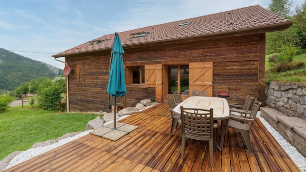 Une cabane en bois avec un patio, une table et des chaises, et une vue sur le paysage environnant.
