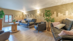 Un salon moderne comprenant un canapé, des fauteuils, une table basse et des panneaux muraux décoratifs en bois.