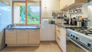 Une cuisine moderne avec des meubles en bois, une grande fenêtre et une cuisinière en acier inoxydable.