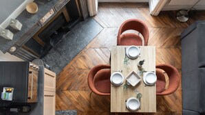 A dining area with a wooden table set for four, surrounded by two orange chairs. - Fenêtre sur cour - Studio pour 2 (Lyon)