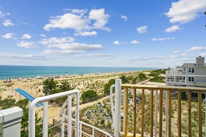 A beach view with a wooden deck, a lifeguard tower, and a building with multiple balconies.