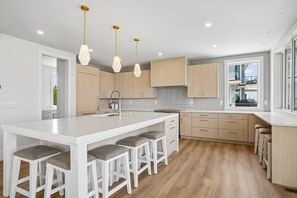 Una cocina moderna con una isla grande, armarios de madera e iluminación colgante.