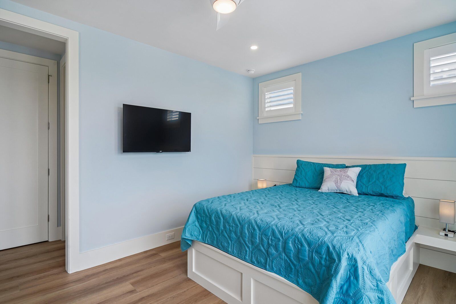 A bedroom with a bed, a television, and a window with blinds.