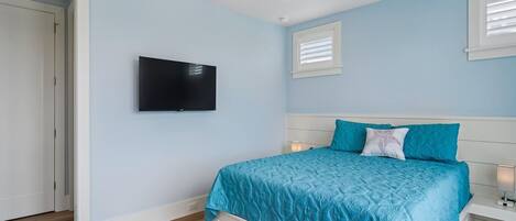 A bedroom with a bed, a television, and a window with blinds.