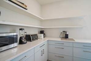 A kitchen with a microwave, toaster, blender, coffee maker, and a coffee machine on the counter.