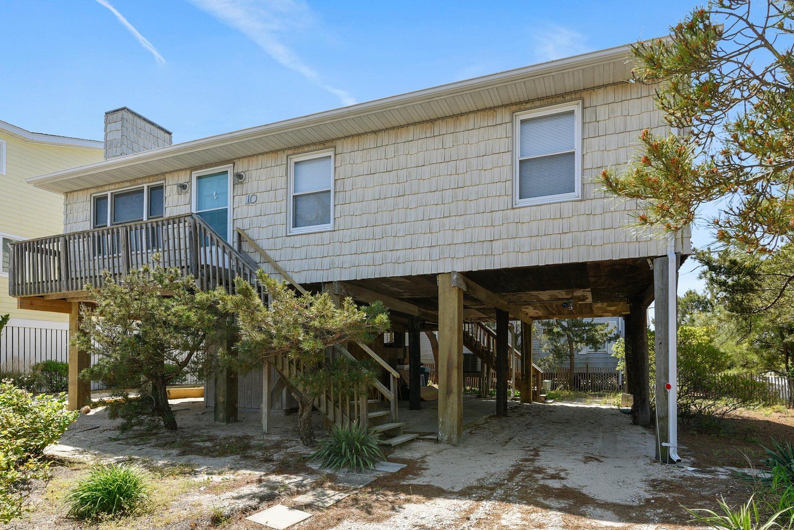 A two-story house with a covered porch, a staircase, and a fenced yard.