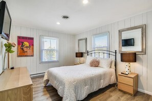 Una camera da letto con un letto, comodini, una televisione e un quadro appeso al muro.