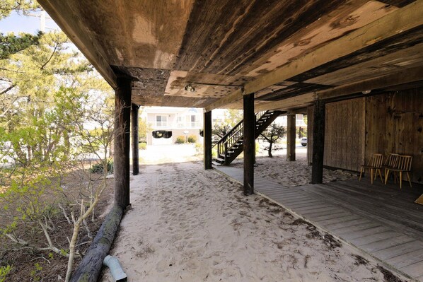 A covered outdoor area with a wooden deck, a staircase, and a view of a building in the background.