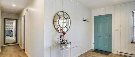 A hallway with a white door, a blue door, and a mirror on the wall.