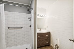 Une salle de bain avec une douche, un lavabo et un meuble-lavabo.