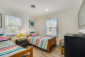 Une chambre avec deux lits simples, un bureau avec un ordinateur et une chaise.
