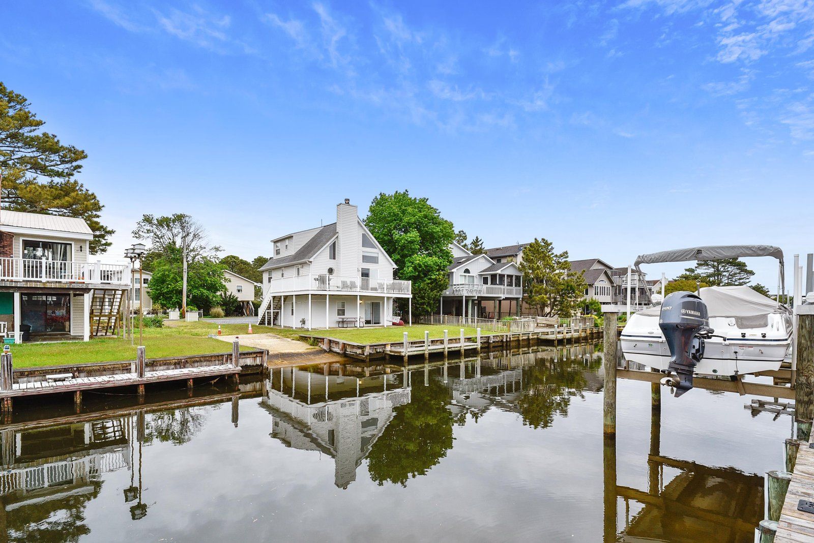 A waterfront property with a dock, a boat, and a house with a balcony.