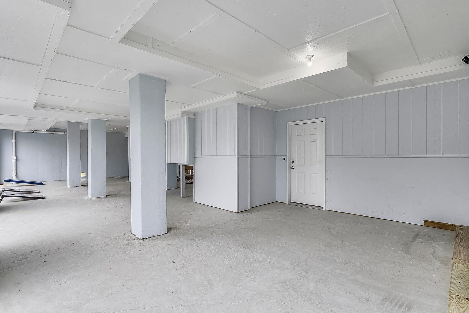 Ein geräumiger Raum mit weißen Wänden und hoher Decke, mit einer Tür und einer sichtbaren Ecke.