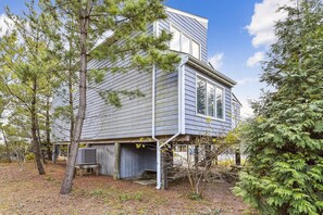 A two-story house with a deck, surrounded by trees.
