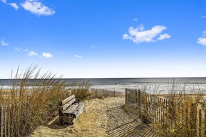 A sandy beach with a wooden bench and a wooden fence. - Charming Oceanside Saltbox Style Home in Bethany Beach! (South Bethany)