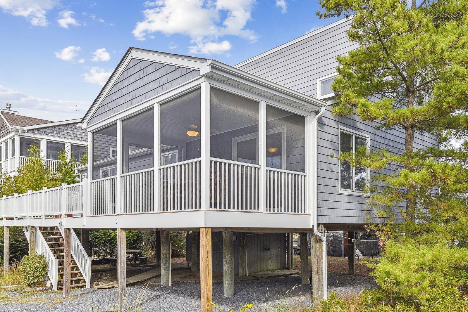A two-story house with a covered porch and a staircase leading to the upper level.