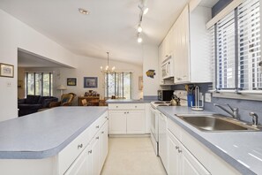A modern kitchen with white cabinets, a central island, and a built-in oven. - Charming Oceanside Saltbox Style Home in Bethany Beach! (South Bethany)
