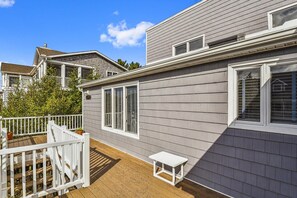 A residential building with a grey siding exterior, a white fence, and a wooden deck. - Charming Oceanside Saltbox Style Home in Bethany Beach! (South Bethany)