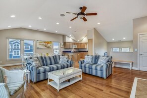 A spacious living room with a high ceiling, a ceiling fan, and a view of the kitchen through an open door. - Amazing 6 BR Oceanside Property in Bethany Beach: Elevator, Hot Tub, Sleeps 15! (South Bethany)