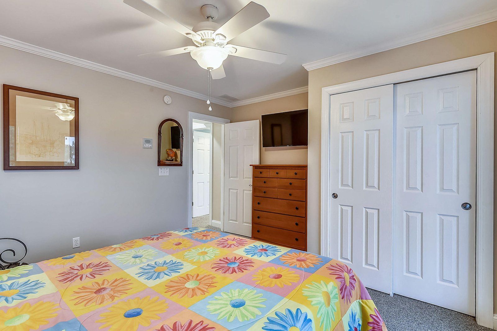 Une chambre à coucher avec un lit, une commode, un ventilateur de plafond et une porte.