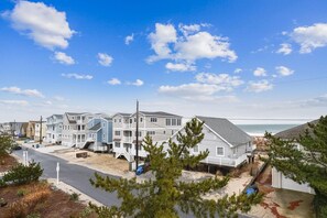 A beachfront residential area with multi-story houses, a clear sky, and a visible ocean. - Amazing 6 BR Oceanside Property in Bethany Beach: Elevator, Hot Tub, Sleeps 15! (South Bethany)