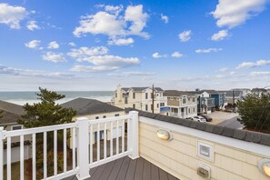 A coastal residential area with houses, a wooden deck, and a view of the ocean. - Amazing 6 BR Oceanside Property in Bethany Beach: Elevator, Hot Tub, Sleeps 15! (South Bethany)