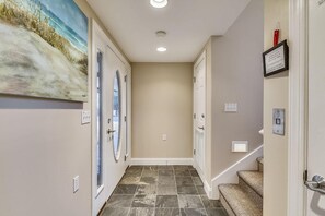 A hallway with two doors, a painting on the wall, and a staircase. - Amazing 6 BR Oceanside Property in Bethany Beach: Elevator, Hot Tub, Sleeps 15! (South Bethany)