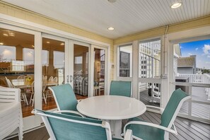 Enjoy meals al fresco in this outdoor dining area with a round table and six chairs, surrounded by a glass door and offering views of the surrounding area.