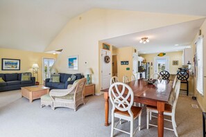 A spacious living area with a sofa, coffee table, and dining table set for four.