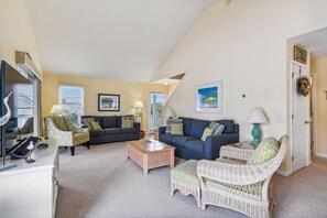 Ein Wohnzimmer mit zwei Sofas, einem Couchtisch und Korbstühlen.