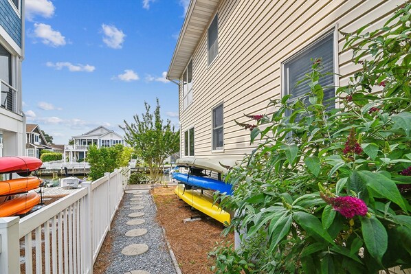 A narrow pathway leading to a house with a small deck area.