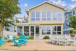 A two-story house with a balcony, outdoor seating, and a wooden deck.