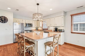 A modern kitchen with a central island, stainless steel appliances, and a chandelier.