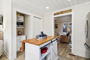 Une cuisine de taille réduite, dotée d’un plan de travail en bois, de meubles blancs et d’un réfrigérateur.