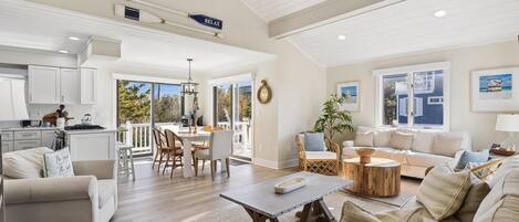 A spacious living area with a dining table, sofas, and a kitchen in the background.