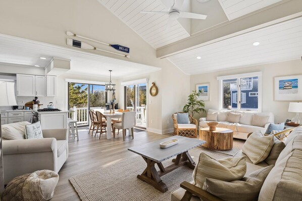 A spacious living area with a dining table, sofas, and a kitchen in the background.
