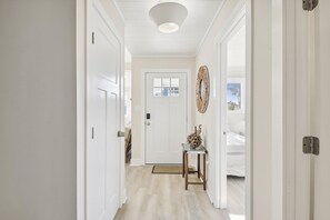A hallway with white doors, a small table with a decorative item, and a ceiling light fixture.