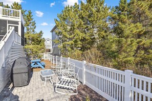 Un jardin avec une clôture blanche, du mobilier d’extérieur et un barbecue.