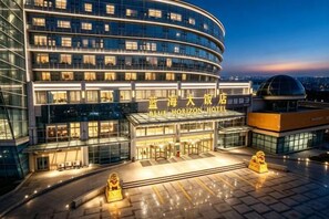 A modern hotel with a curved facade, multiple floors, and a prominent entrance with a glass canopy.