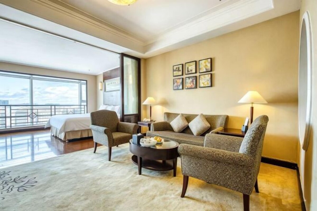 A hotel room with a balcony, a sofa set, a coffee table, and a bed.