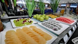 Un bufet amb una varietat de fruites i verdures, incloent raïm, pomes verds i talls de meló.