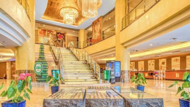 Un vestíbul ampli amb una imponent escala, paviment de marbre i una decoració moderna.