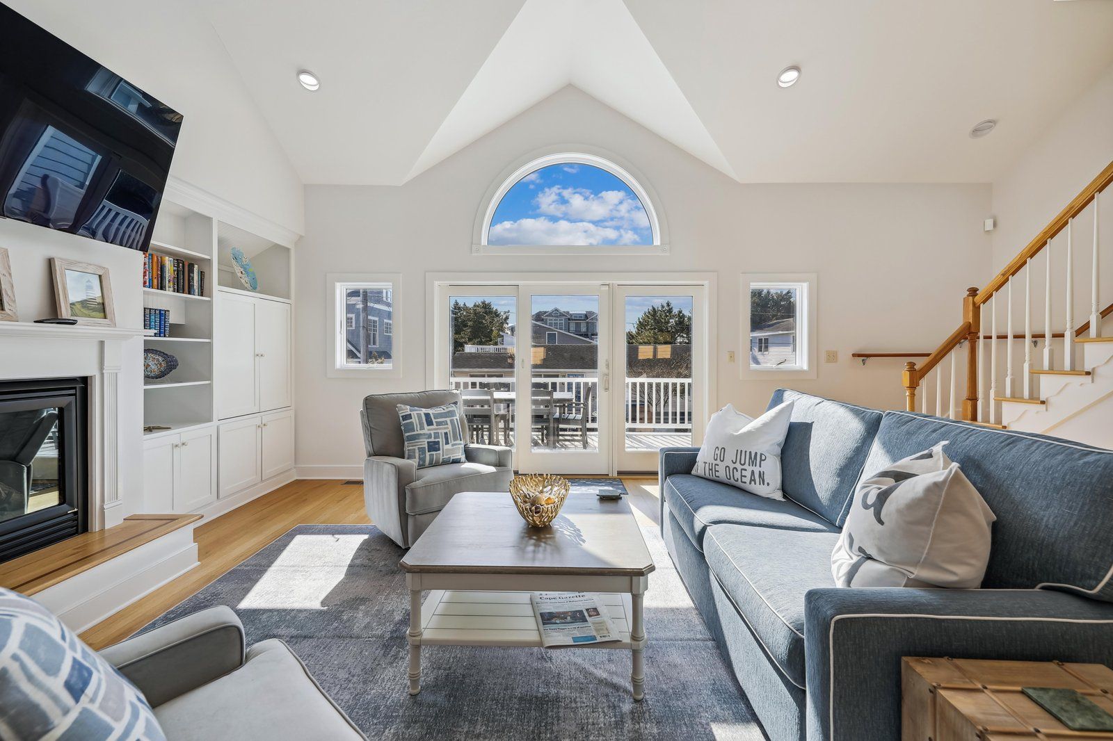 A spacious living room with a fireplace, a large window, and a view of the outside.