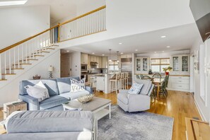 A spacious living area with a staircase, a kitchen, and a dining area.