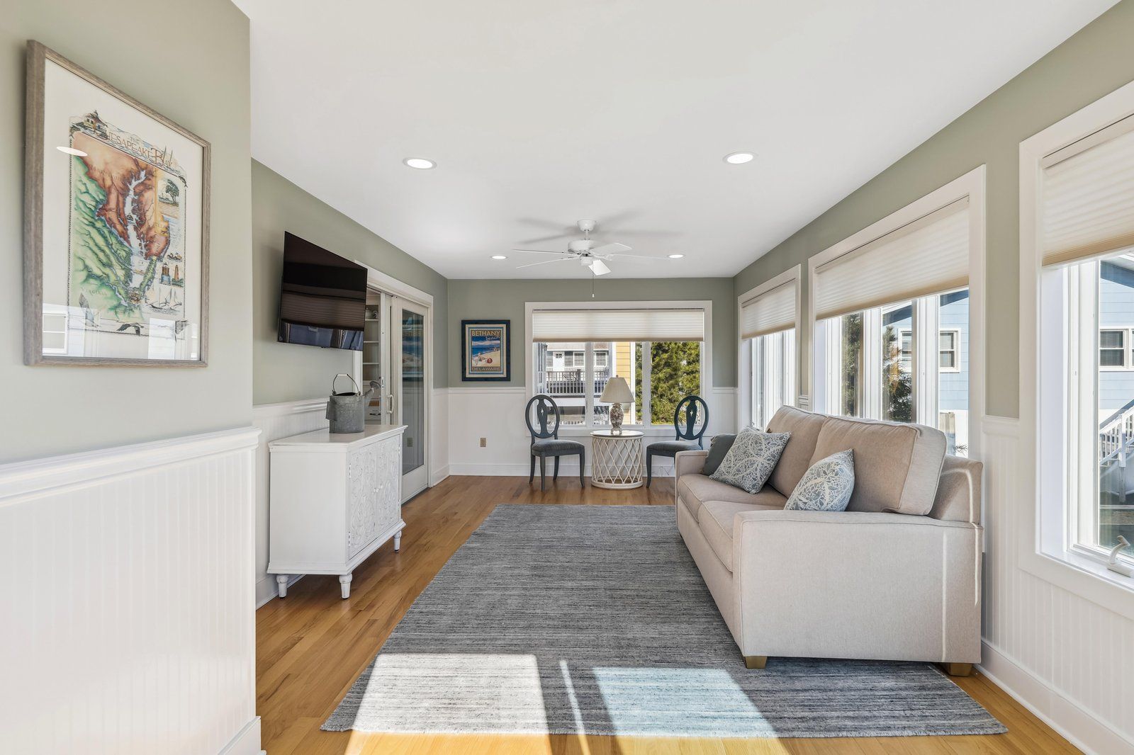 A spacious living area with a sofa, a dining table, and a kitchen area with a refrigerator and cabinets.
