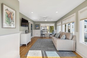 A spacious living area with a sofa, a dining table, and a kitchen area with a refrigerator and cabinets.